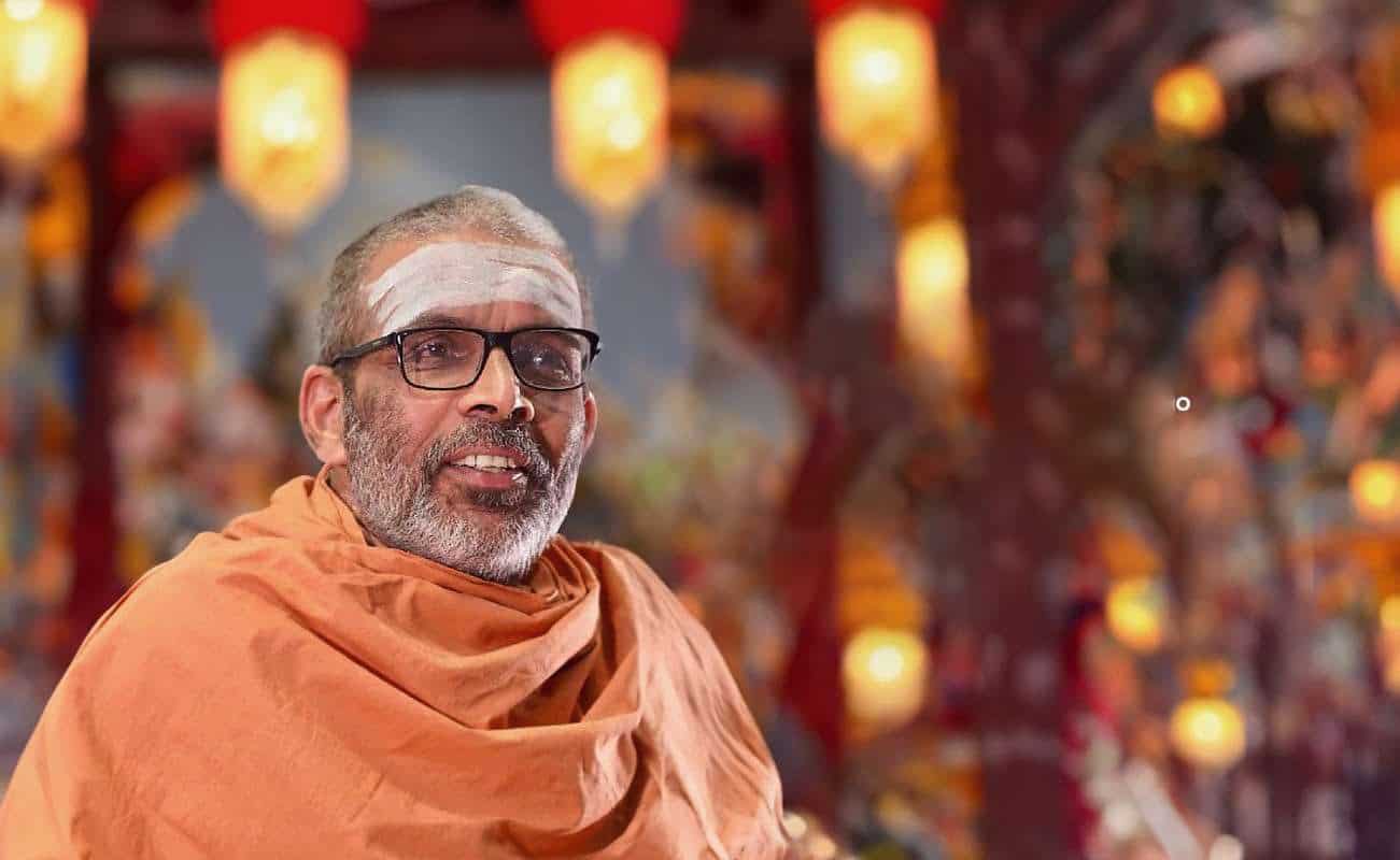 Spiritual leader wearing traditional robes and glasses at a cultural event.